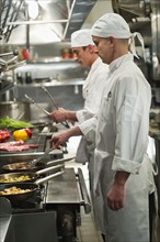 Chefs preparing food in kitchen.