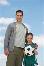 Portrait of father and daughter (8-9) with soccer ball.
