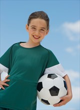 Portrait of girl (8-9) holding soccer ball.