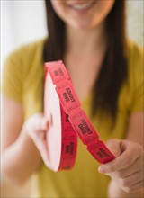 Close up of woman holding tape with "admit one" tickets in roll. Photo : Jamie Grill Photography