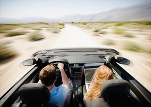 Couple driving through desert in convertible car. Photo : Jamie Grill Photography