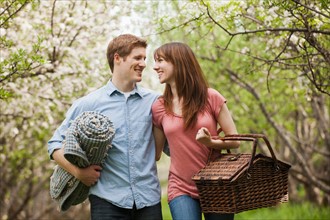 Young couple with picnic basket in orchard. Photo : Mike Kemp