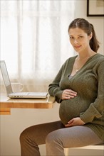 Portrait of expecting mother with laptop. Photo : Rob Lewine