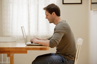 Man using laptop at home. Photo : Rob Lewine