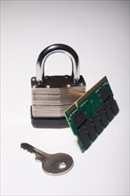 Close-up studio shot of silver padlock with key and computer chip. Photo : Winslow Productions