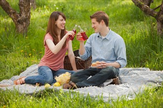USA, Utah, Provo, Young couple toasting drinks during picnic. Photo : Mike Kemp