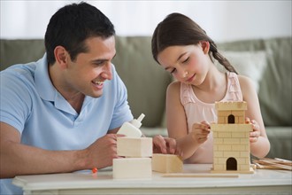 Father and daughter (8-9) building toy castle.