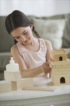 Girl (8-9) building toy castle.