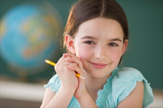 Portrait of girl (8-9) holding pencil.