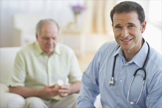 Portrait of male doctor with senior patient in background.