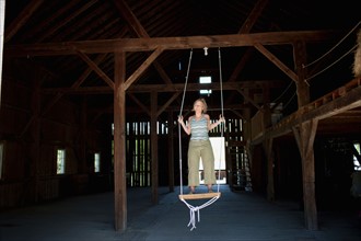USA, Vermont, Dorset, Woman on swing in barn. Photo : Noah Clayton