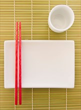Chopsticks, plate and mug on bamboo mat. Photo : Daniel Grill