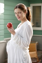 Portrait of expecting mother eating apple. Photo : Rob Lewine