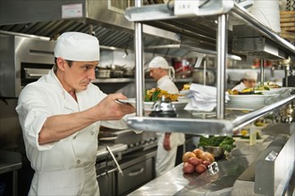 Chefs preparing food in kitchen.