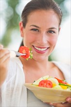Portrait of young woman eating salad.