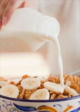 Close up of hand pouring milk into bowl of cereals. Photo: Jamie Grill