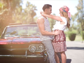 Couple embracing near convertible car. Photo : db2stock