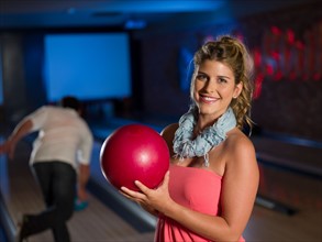 Smiling woman holding bowling ball at alley. Photo: db2stock