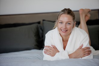 Portrait of mature woman lying on bed. Photo : Rob Lewine