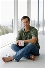 Mature man relaxing with coffee cup. Photo : Rob Lewine