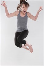Portrait of young woman jumping, studio shot. Photo : Rob Lewine