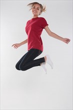 Portrait of teenage girl (16-17) jumping, studio shot. Photo: Rob Lewine