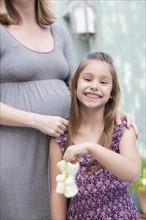 Pregnant mother standing with daughter (6-7) holding baby booties . Photo : Rob Lewine