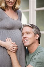 Man with head next to pregnant woman's belly . Photo : Rob Lewine