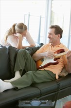 Mature man playing guitar while woman listening. Photo : Rob Lewine
