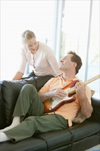 Mature man playing guitar while woman listening. Photo : Rob Lewine