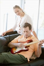 Mature man playing guitar while woman listening. Photo: Rob Lewine