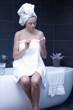 Mature woman sitting in bathroom wrapped in towel. Photo: Rob Lewine