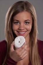 Portrait of teenage girl (16-17) with donut, studio shot. Photo : Rob Lewine