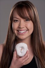 Portrait of young woman with donut, studio shot. Photo : Rob Lewine