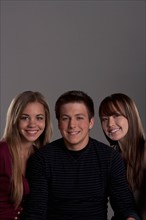 Portrait of teenage boy (16-17) and girl (16-17) with young friend, studio shot. Photo: Rob Lewine