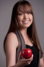Portrait of teenage girl (16-17) with red apple, studio shot. Photo : Rob Lewine