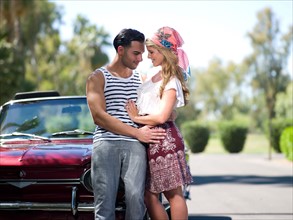 Couple embracing near convertible car. Photo : db2stock