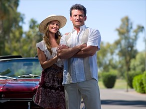 Smiling couple standing near convertible car. Photo : db2stock