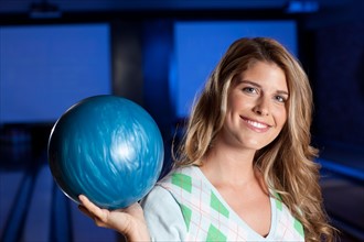 Young smiling woman holding bowling ball. Photo : db2stock