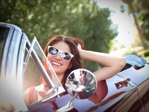 Smiling young woman in convertible car. Photo: db2stock