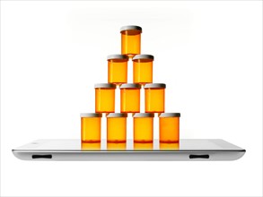 Studio shot of stack of pill bottles on digital tablet. Photo : David Arky