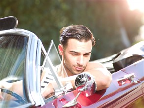 Smiling young man in convertible car. Photo: db2stock
