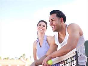 Smiling couple standing near tennis net. Photo: db2stock