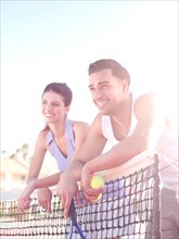 Smiling couple standing near tennis net. Photo: db2stock