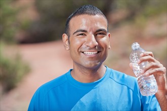 Smiling man drinking water after jogging. Photo : db2stock