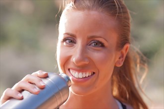 Smiling woman drinking water after jogging. Photo: db2stock