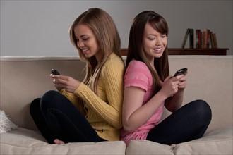 Portrait of teenage girl (16-17) with young woman sitting on sofa. Photo : Rob Lewine