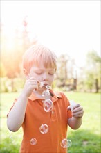Boy (2-3) blowing bubbles in park. Photo: Take A Pix Media