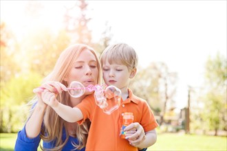 Mother and son (2-3) blowing bubbles in park. Photo: Take A Pix Media