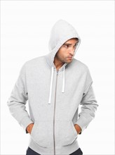 Young man in hoodie standing with hands in pockets. Photo: momentimages